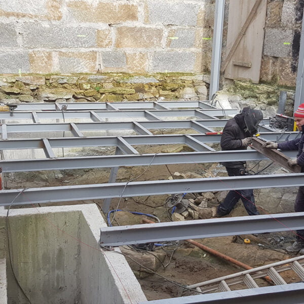 Operarios instalando estructura metálica en suelo de edificio